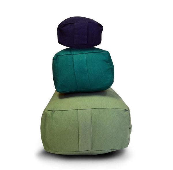 (bottom to top) Supportive rectangular bolster in sage, small rectangular bolster in green, pranayama bolster in blue.